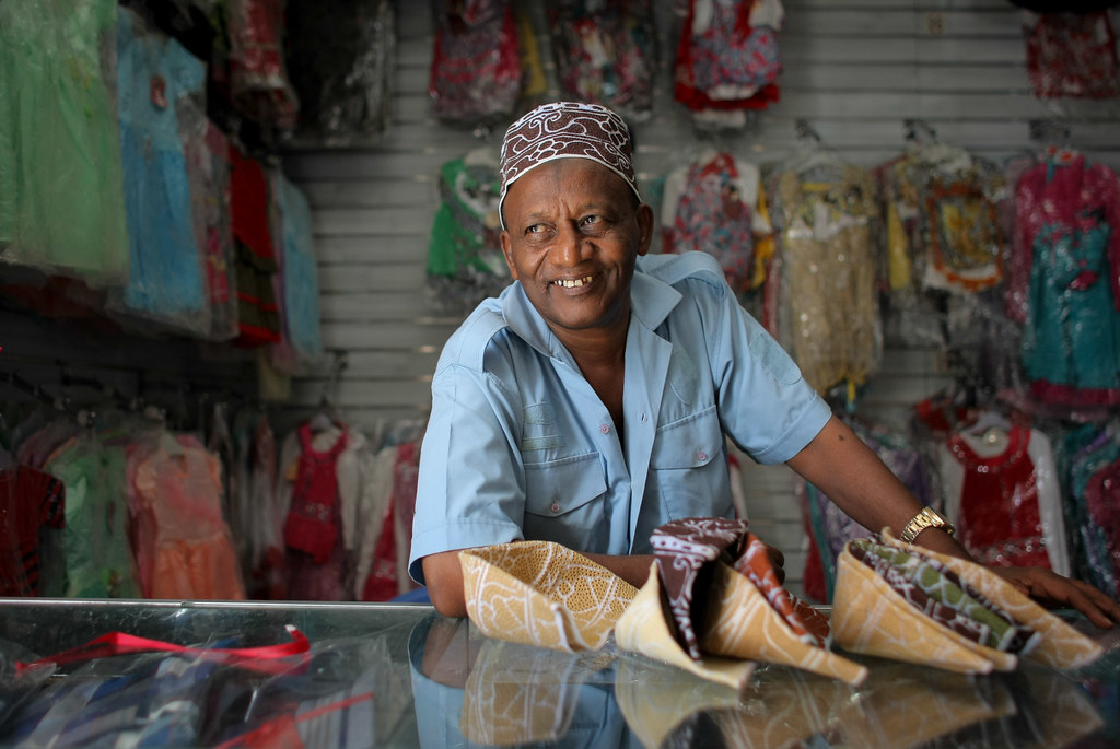 A shopkeeper smiling behind the counter of his shop in East Africa